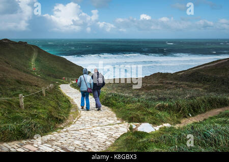 Menschen gehen auf dem Küstenweg an Bedruthan Steps auf der nördlichen Küste von Cornwall. Stockfoto