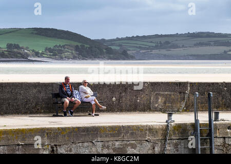 Padstow Hafen - ein Paar auf einer Bank sitzen und genießen die Sonne am Hafen in Padstow an der Küste von North Cornwall. Stockfoto