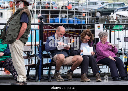 Padstow - Urlauber, die einen Urlaub verbringen, entspannen sich und essen Fisch und Chips am Hafen in Padstow an der Küste von Nord-Cornwall. Stockfoto