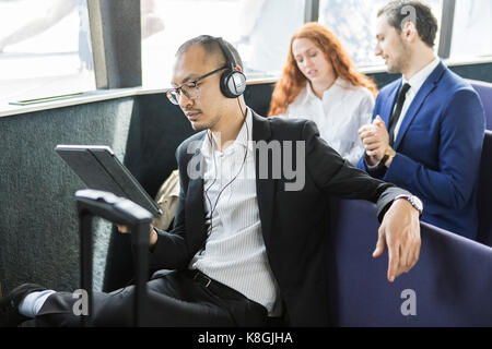 Unternehmer hören kopfhörer bei digitalen Tablette auf der Fähre suchen Stockfoto