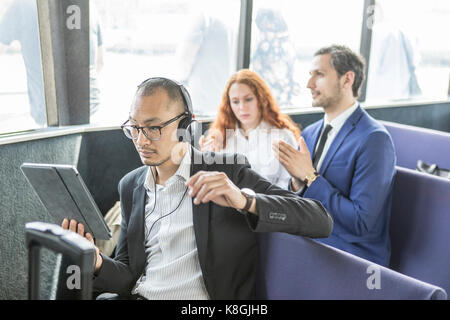 Unternehmer hören kopfhörer bei digitalen Tablette auf der Fähre suchen Stockfoto