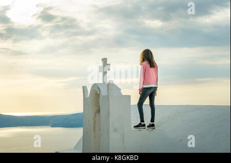 Stehendes Mädchen auf Kirche, Perissa, Santorini, Griechenland Kikladhes Stockfoto