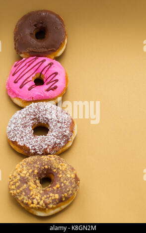 Köstliche sortierten Donuts mit Rosa, Schokolade, Kokos, Erdnuß verglaste in einer Linie über eine hölzerne Hintergrund untergebracht Stockfoto