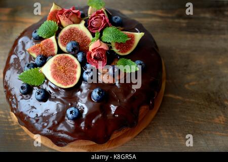 Сhocolate Kuchen mit Feigen, Beeren, Nüsse, Minze und Rosen dekoriert Stockfoto