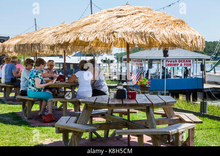 North Carolina, North Carolina, North Carolina, Calabash, Fischerdorf, Meeresfrüchte, regionale Küche, Abendessen, Außenterrasse mit Tischen im Freien, Strohschirm, Captain Nance's Sea Stockfoto