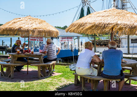 North Carolina, North Carolina, North Carolina, Calabash, Fischerdorf, Meeresfrüchte, regionale Küche, Abendessen, Außenterrasse mit Tischen im Freien, Strohschirm, Fischerboot, Dock, Ca Stockfoto