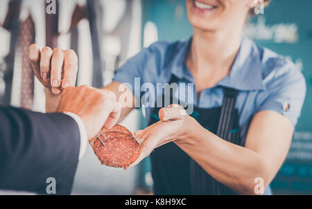 Arbeiten in einem Metzger shop-Shop Assistant übergabe Fleisch an Kd Stockfoto