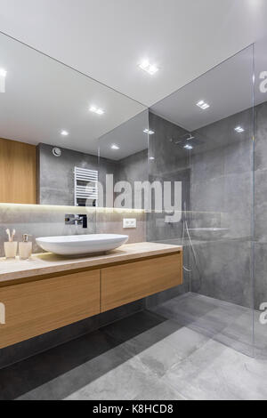Badezimmer mit grauen lange Arbeitsplatte, Spiegel und begehbarer Dusche Stockfoto