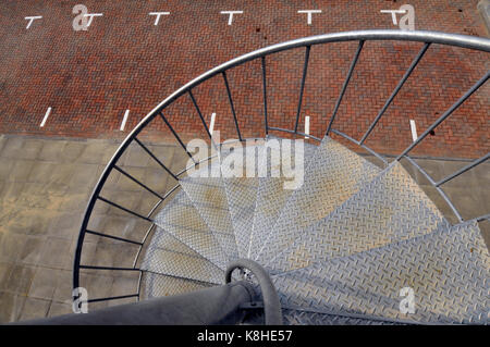 Eine Wendeltreppe aus verzinktem Stahl, die zu einem Parkplatz auf der Außenseite eines modernen Bürogebäudes. Stockfoto