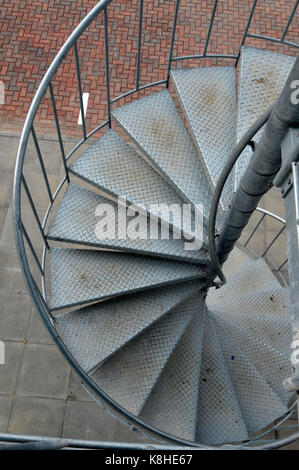 Eine Wendeltreppe aus verzinktem Stahl, die zu einem Parkplatz auf der Außenseite eines modernen Bürogebäudes. Stockfoto