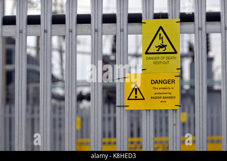 Eine Elektrizitätsgesellschaft sub Station mit palisade Fencing und Gefahr, die Gefahr des Todes gelbe Schilder auf die Einzäunung angebracht als Warnungen auf Eindringlinge Stockfoto