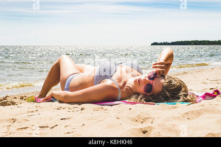 Frau im Bikini liegen auf Sand am Strand gegen Himmel im Sommer Stockfoto