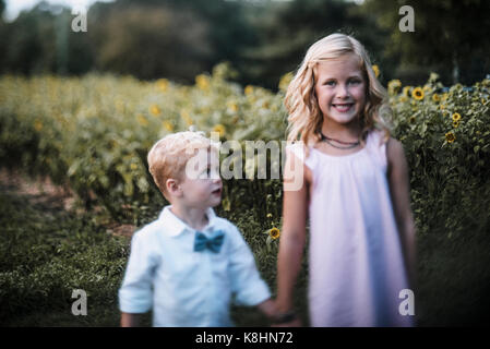 Portrait von Happy Schwester mit Bruder auf Sonnenblumenfeld Stockfoto