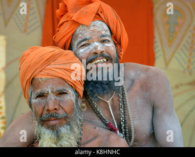 Zwei glückliche indisch-hinduistischen sadhus mit orangefarbenen Turbanen und Heilige weiße Asche alle über ihre Gesichter, Bärte und Einrichtungen, Umarmen in enger Umarmung Stockfoto