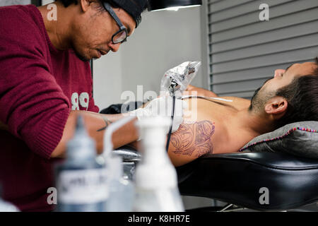 Tattoo artist tattooing Schulter des Menschen Stockfoto