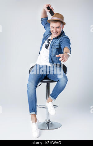 Schöner Mann in Jeans sitzt auf Stuhl Stockfoto