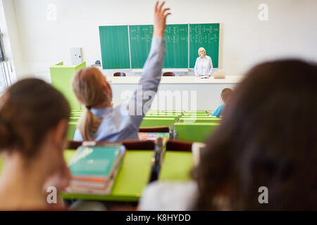 Fleißige Schüler hebt die Hand in der Universität Hörsaal und Antworten Lehrer frage Stockfoto