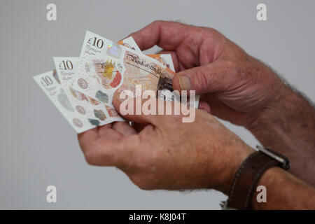 Ein Mann dargestellt, die eine neue zehn Pfund Hinweis in seinem Haus in Chichester, West Sussex, UK. Stockfoto