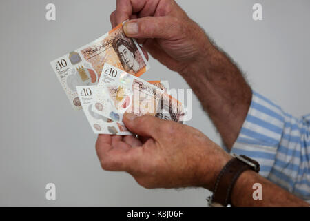 Ein Mann dargestellt, die eine neue zehn Pfund Hinweis in seinem Haus in Chichester, West Sussex, UK. Stockfoto