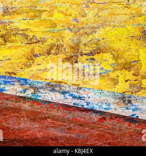Ein Quadrat Zusammenfassung von Gelb Blau Rot und Weiß. Die abblätternde Farbe war auf der Seite von einem hölzernen Angeln Boot von Sea Adventures und Wetter erodiert. Stockfoto