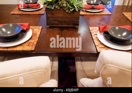 Einen warmen Speisesaal mit grauen Schalen und tan Stühle an einem braunen Tisch. Stockfoto