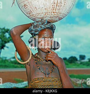 Fulani Milchdienstmädchen. Calabash, mit Hand eingeschnitten, Dekoration, auf ihrem Kopf ausgeglichen. Hinweis für Gesicht und Oberkörper scarifications Markierungen als Dekoration. C Stockfoto