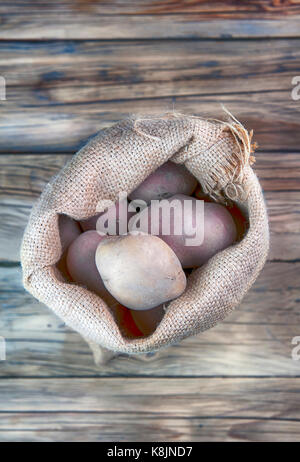 Ernte Kartoffeln in sackleinen Sack auf Holz- Hintergrund Stockfoto