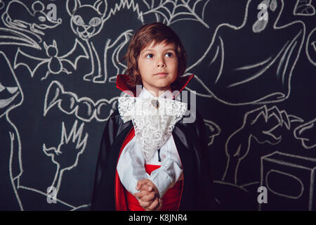 Junge in Scary Hallowe'en Kostüme auf dunklem Hintergrund mit Halloween Illustrationen. Dracula. Stockfoto