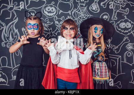 Kinder in Scary Halloween Kostüme stehen gegen eine Wand mit Zeichnungen. Stockfoto