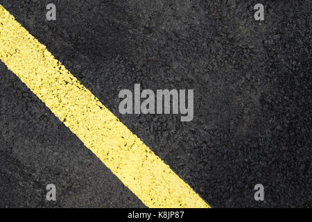 Grunge, schmutzigen Blick auf Asphalt mit deutlichen gelben Streifen Stockfoto