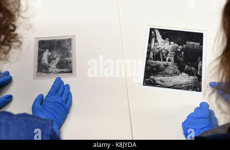 Kuratoren prüfen eine Radierung "Die Enthauptung Johannes des Täufers" (links) und "Die Kreuzabnahme im Fackelschein" (rechts), auf dem Display während der Rembrandt: Blitz die Dunkelheit Ausstellung in Norwich Castle Museum & Art Gallery. Stockfoto