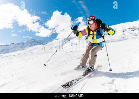 Eine männliche Skifahrer Skifahren nach unten Berghang Piste in der Nähe von Kamera auf einem sonnigen blauen Himmel tag Winter, 3 Täler, Meribel, Frankreich Stockfoto