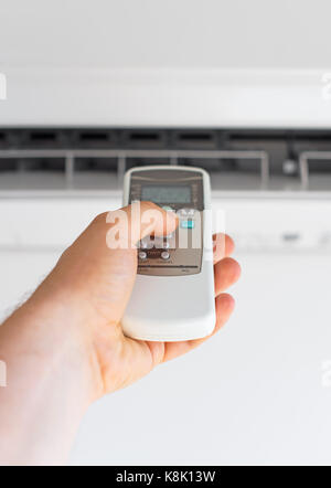 Hand, die Fernbedienung auf die Klimaanlage. Stockfoto