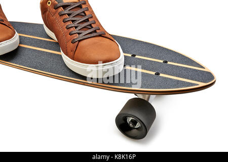 Dynamische Seitenansicht eines Schwarzen und Holz- Skate Board und braun Leder Schuhe auf einen weißen Hintergrund mit Freistellungspfad isoliert Stockfoto