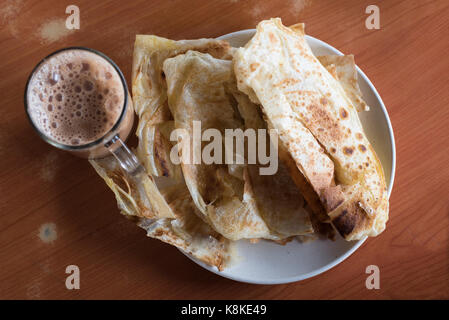 Fladenbrot und Tee mit Milch. Auch als Roti Canai und Teh Tarik vom malaysischen Menschen. Es ist eine berühmte und beliebte Mahlzeit in Malaysia. jeden Tag essen Stockfoto