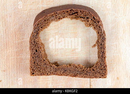 Die Masse der Roggen Brot gegessen. Salzkruste gebackenem Brot, liegend auf einem hölzernen Schneidebrett ohne Kern. Foto Nahaufnahme, Ansicht von oben Stockfoto