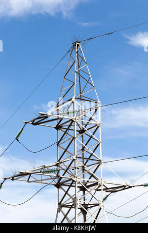 Hochspannungsleitungen auf Metall Beiträge auf dem Hintergrund des blauen Himmels installiert. Foto close-up. auf den Drähten gibt es Glasisolatoren Stockfoto