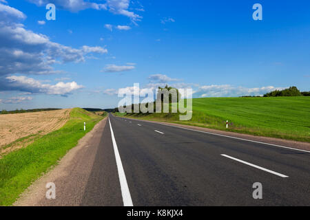 Landschaft mit einer asphaltierten Schnellstraße im Frühjahr Saison. An den Rändern der Straße gibt es Berge, auf denen wächst Gras, Pflanzen und Bäume Stockfoto