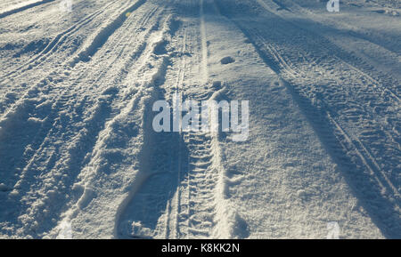 Grobe Kurve Straße im Winter, bedeckt mit Schnee und Eis. Auf der Oberfläche, Schatten von wachsenden Bäumen sichtbar sind. Foto über die Straße genommen Stockfoto