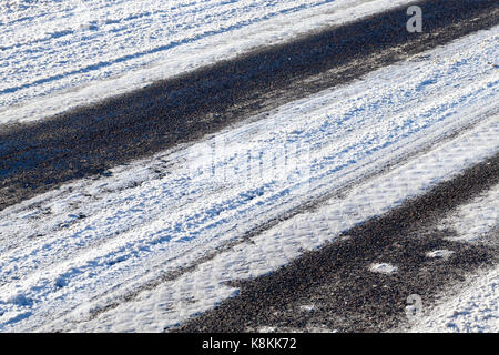 Anschluss von den Rädern des Autos auf die Schnee-bedeckten Asphalt der Straße. Nahaufnahme fotografiert. Stockfoto