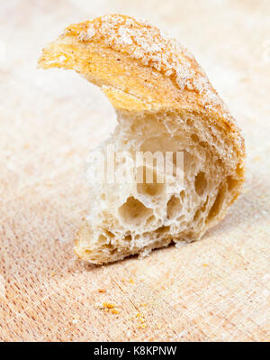 Halb gegessen Stück licht Baguette aus Weizenmehl. Foto in der Nähe von Brot liegen auf einem Holzbrett Stockfoto