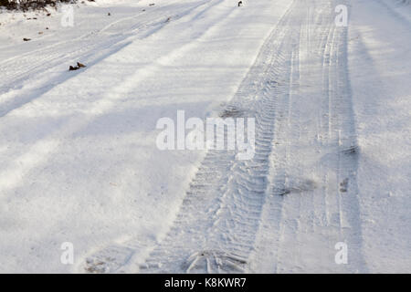 Die Markierungen der Räder des Fahrzeugs auf schneebedeckten Straßen. In der Nähe fotografiert. Stockfoto