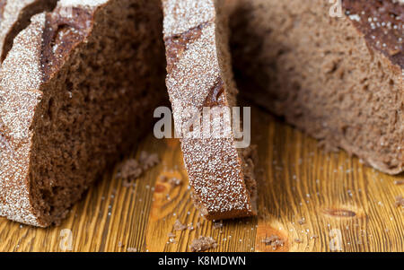 Ein paar Stücke vonschneiden schwarz Roggenbrot, liegend auf einem braunen Tisch. Foto close-up. Fokus in der Mitte des Rahmens Stockfoto