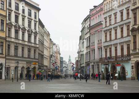 Straße, die auf den Rynek Glowny in der Altstadt von Krakau führt, mit historischen Gebäuden und Fußgängern, Polen. Stockfoto