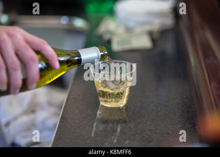Barkeeper gießen Weißwein in eine kleine Schale aus Kunststoff Stockfoto