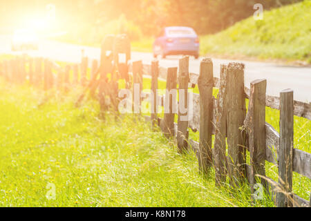 Ländliche Straße mit einer alten hölzernen Zaun mit solar Wirkung Stockfoto