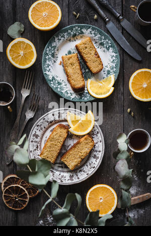 Orange Kuchen serviert auf vintage Platten auf rustikalen Holztisch Hintergrund. Essen still life. Ansicht von oben, vertikalen Zusammensetzung Stockfoto