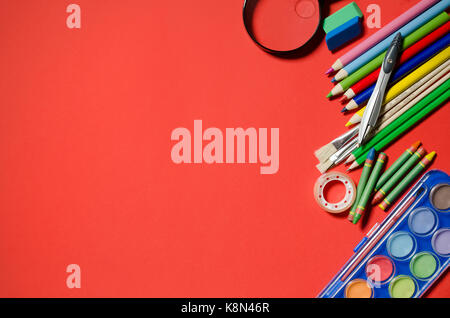 Schule und Büro Schreibwaren, roten Hintergrund, Copyspace. Stationery Office desk top Ansicht Tabelle Schüler Konzept Stockfoto