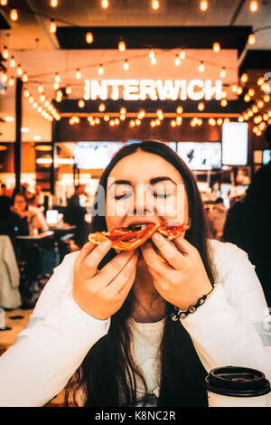 New York, USA - 30. September 2016: Junge Frau essen Pizza in LaGuardia Airport beim Warten auf ihren Flug. Stockfoto