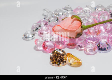 Gold Edelsteine glänzen Licht Anhänger vor rosa Rose Blume. Stockfoto